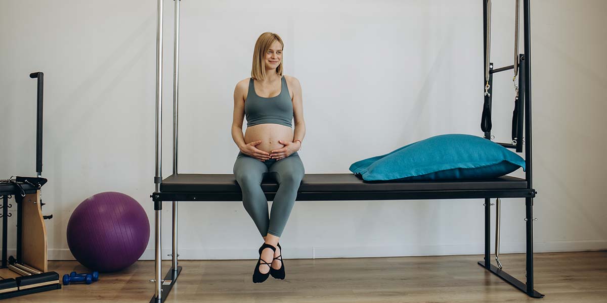 Mulher gestante sentada em estúdio de pilates