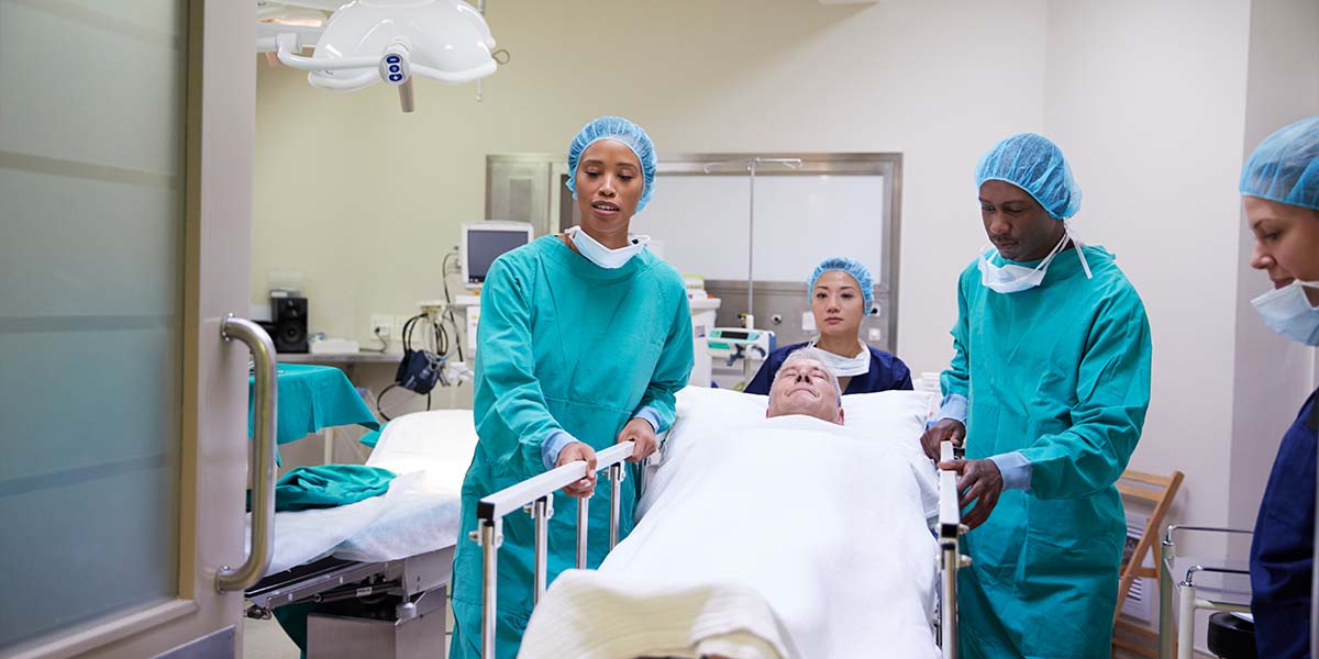 Paciente deitado em maca sendo levado da sala de cirurgia por enfermeiros.Dr.Luiz Gustavo - cirurgião bariátrico no Rio de Janeiro -RJ
